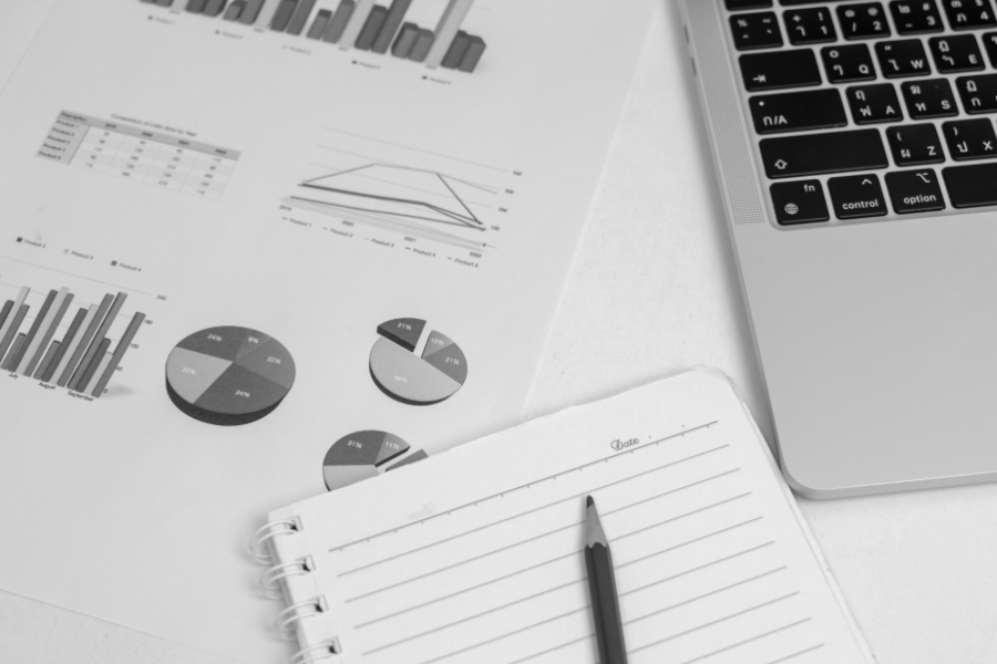 Raport finansowy z wykresami obok laptopa i notesu.